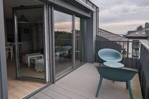 Ein Balkon mit einer Schiebetür zu einem Raum, einem kleinen Tisch und einem Stuhl.