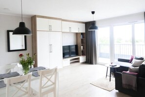 Ein modernes Wohnzimmer mit Fernseher, Esstisch und Sitzecke.