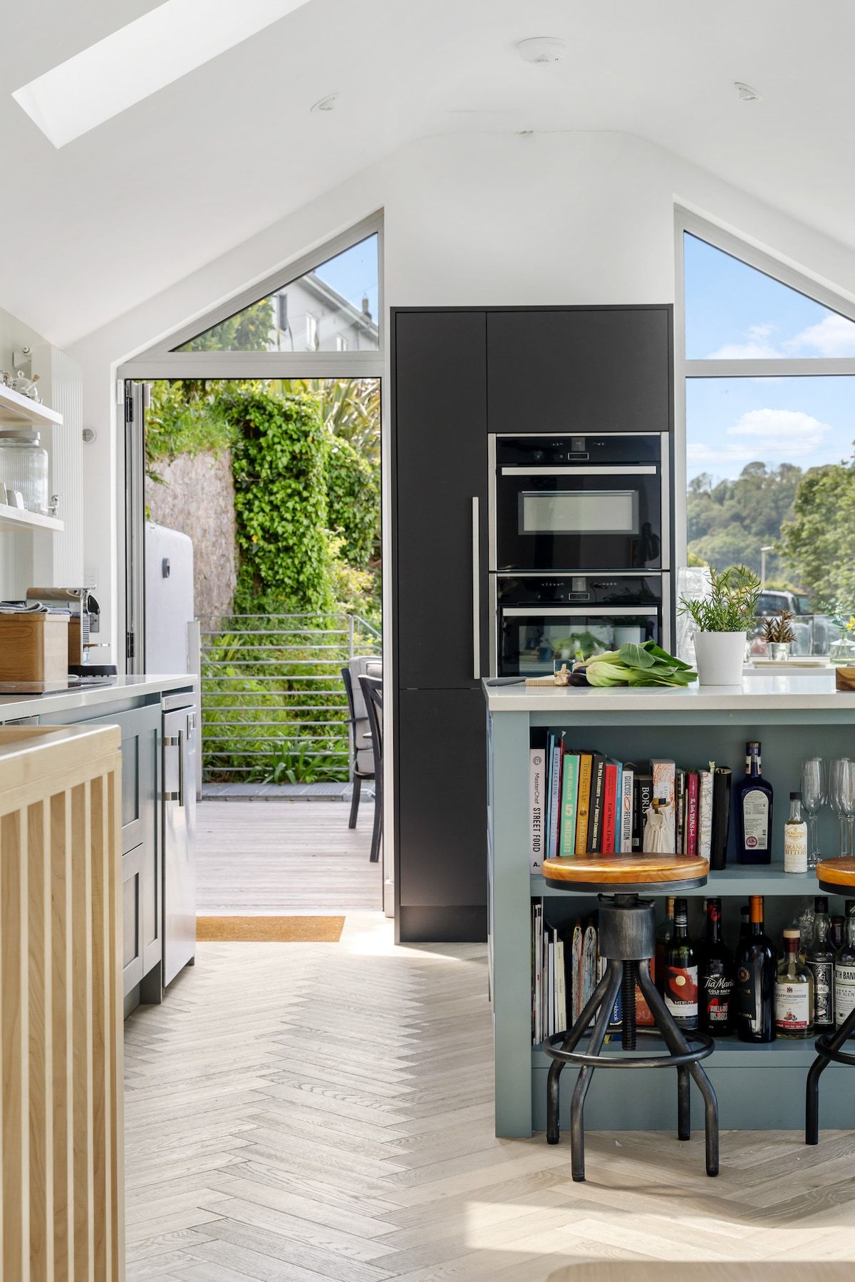 A modern kitchen with an open layout, a built-in oven, and a dining area with a bookshelf.