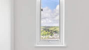 A room with a window overlooking a landscape, a chair with a yellow blanket, and a white radiator.