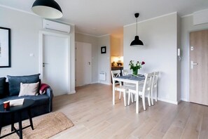 A modern living room with a sofa, a dining table with chairs, and a kitchen area in the background. - Cozy Apartment for 4 in West Pomeranian (Dziwnow)