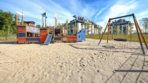 A playground with various play structures, including slides and swings, on a sandy surface.