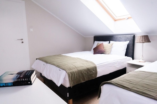 A bedroom with a bed, a bedside table, a lamp, and a book.