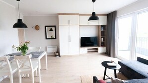 A modern living room with a dining area, a TV, and a large window.