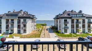 A modern apartment building with balconies, a parking area, and a view of the sea.