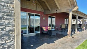 A covered patio with stone walls, a glass door entrance, and outdoor furniture. - Lake Roosevelt Retreat - Spring Canyon Boat Launch (Grand Coulee)