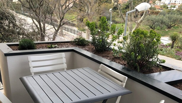 A balcony with a table and chairs, a view of trees and buildings, and a street lamp. - Air-conditioned apartment for 4 near town center. Small dogs accepted (La Londe-les-Maures)