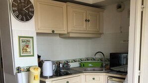 A kitchen with a clock, a coffee maker, a microwave, and a sink. - Air-conditioned apartment for 4 near town center. Small dogs accepted (La Londe-les-Maures)