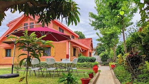 Un edificio con fachada de ladrillo, tejado rojo y un jardín con un sendero pavimentado.