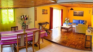 Un comedor con una mesa y sillas, un sofá y una mesita de centro en una habitación con suelo de madera y pared amarilla.