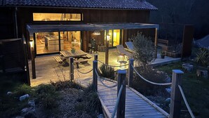 Une maison moderne dotée d’un patio, d’une terrasse en bois et d’un espace extérieur aménagé et couvert.