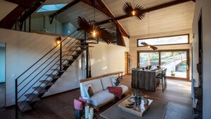 Un vaste espace de vie comprenant un escalier en bois, un canapé, une table basse et un coin repas avec vue.