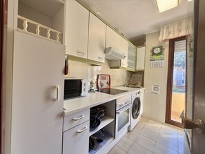 Una cocina equipada con lavadora, microondas y refrigerador.