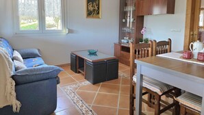 A living room with a sofa, a glass-top coffee table, a wooden cabinet, and a dining table with chairs. - La Encina de Güemes - 13008 (Güemes)