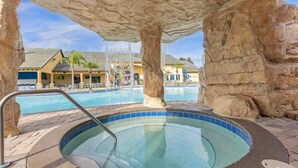 Un bain à remous avec une piscine en arrière-plan, le tout entouré de piliers en pierre.