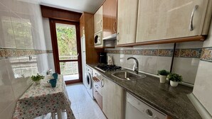 A kitchen with a washing machine, a sink, and a table with a floral tablecloth. - Apartment Playa Azul - 5924 (Isla)