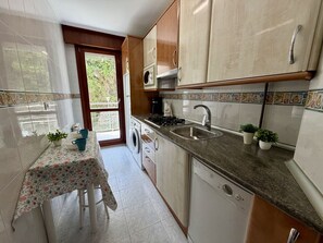 Una cocina con lavadora, un lavamanos y una mesa con mantel floreado.