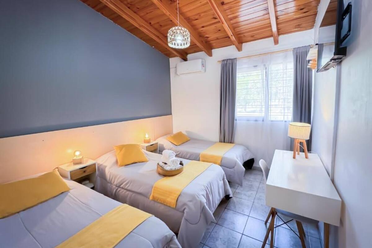 Hotellihuone, jossa on kaksi sänkyä, työpöytä, televisio ja ikkuna, jossa on verhot.