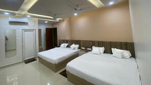 A hotel room with two beds, a ceiling fan, recessed lighting, and a mirror. - R J Residency  (Varanasi)