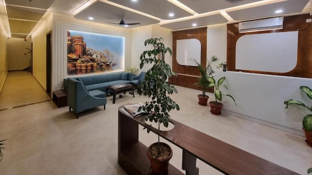 A modern lobby with a blue sofa, potted plants, and a large wall mural. - R J Residency  (Varanasi)