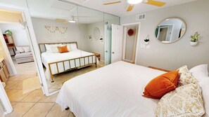 A bedroom with a bed, a ceiling fan, a mirror, and a door leading to another room. - Beautiful Dog Friendly Canal Front 4205 1BR with Free Beach Service for 2! (Destin)