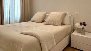 A modern bedroom with a large bed, bedside tables, a nightstand, and a wall-mounted light. - Boutique Apartment 60sqm between Sempione & CityLife with Studio Space (Milano)