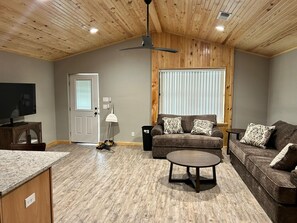A living room with a wooden ceiling, a sofa set, a coffee table, and a television.