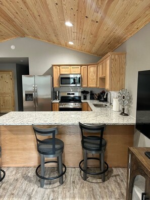 A modern kitchen with wooden cabinets, stainless steel appliances, granite countertops, and two bar stools. - Texas Cabin

Wonderful 3-bedroom triplex in charming Kirby next to the lake. (Kirby)
