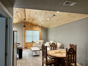 A room with a wooden ceiling, a dining table with chairs, a sofa set, and a window with blinds. - Texas Cabin

Wonderful 3-bedroom triplex in charming Kirby next to the lake. (Kirby)