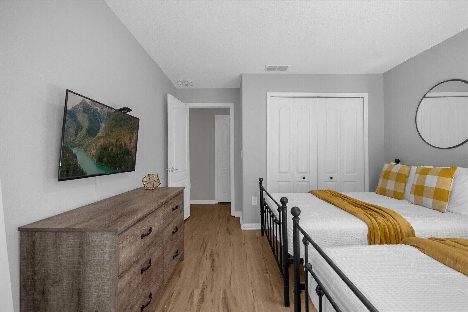 A bedroom with a bed, a dresser, a painting, and a door.