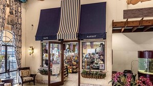 En elegant hotellobby med ett café, utsikt genom fönstret och ett träpanelat tak.