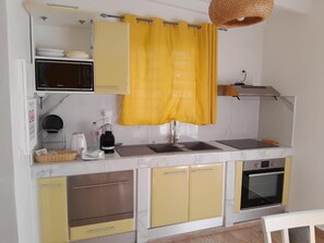A compact kitchen with a microwave, coffee maker, and a sink. - Gîtes Les Colibris Jaunes_Appart. No1_Citronnelle with swimming pool in Marie-Galante (Grand-Bourg de Marie-Galante)