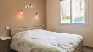Ein Schlafzimmer mit Bett, Fenster und Wandleuchte.