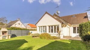 Ein Wohnhaus mit gepflegtem Rasen, Grillplatz und Satellitenschüssel.
