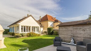 Ein Wohnhaus mit gepflegtem Rasen, einer Sitzgelegenheit im Freien und einem Holzzaun.