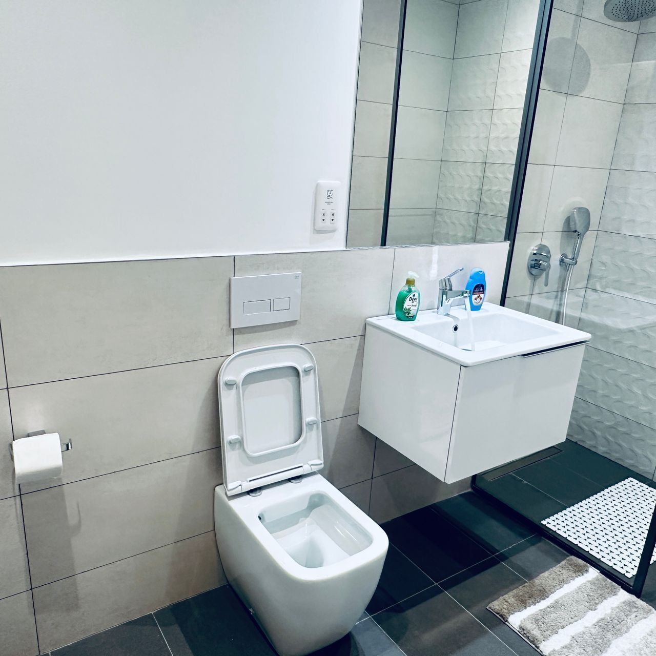 Un baño moderno con inodoro, lavamanos y ducha.