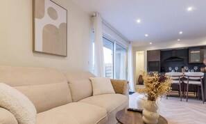 Ein Wohnzimmer mit einer Couch, einem Couchtisch und einer Vase mit Trockenblumen.