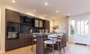 Eine moderne Küche mit dunklen Holzschränken, einem eingebauten Ofen und einem Essbereich mit Tisch und Stühlen.