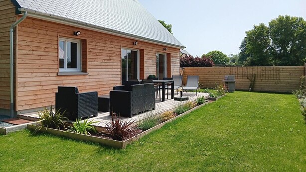 Une maison en bois dotée d’une terrasse, de mobilier d’extérieur et d’une pelouse bien entretenue.