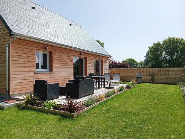 A wooden house with a patio, outdoor furniture, and a well-maintained lawn. - House with AC and pets allowed (La Haye-du-Puits)