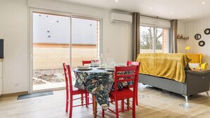 Un coin repas avec une table dressée pour quatre personnes, des chaises rouges et un canapé recouvert d’une housse jaune.