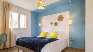 Une chambre à coucher avec un lit, deux lampes de chevet, une fenêtre avec des rideaux et une chaise.