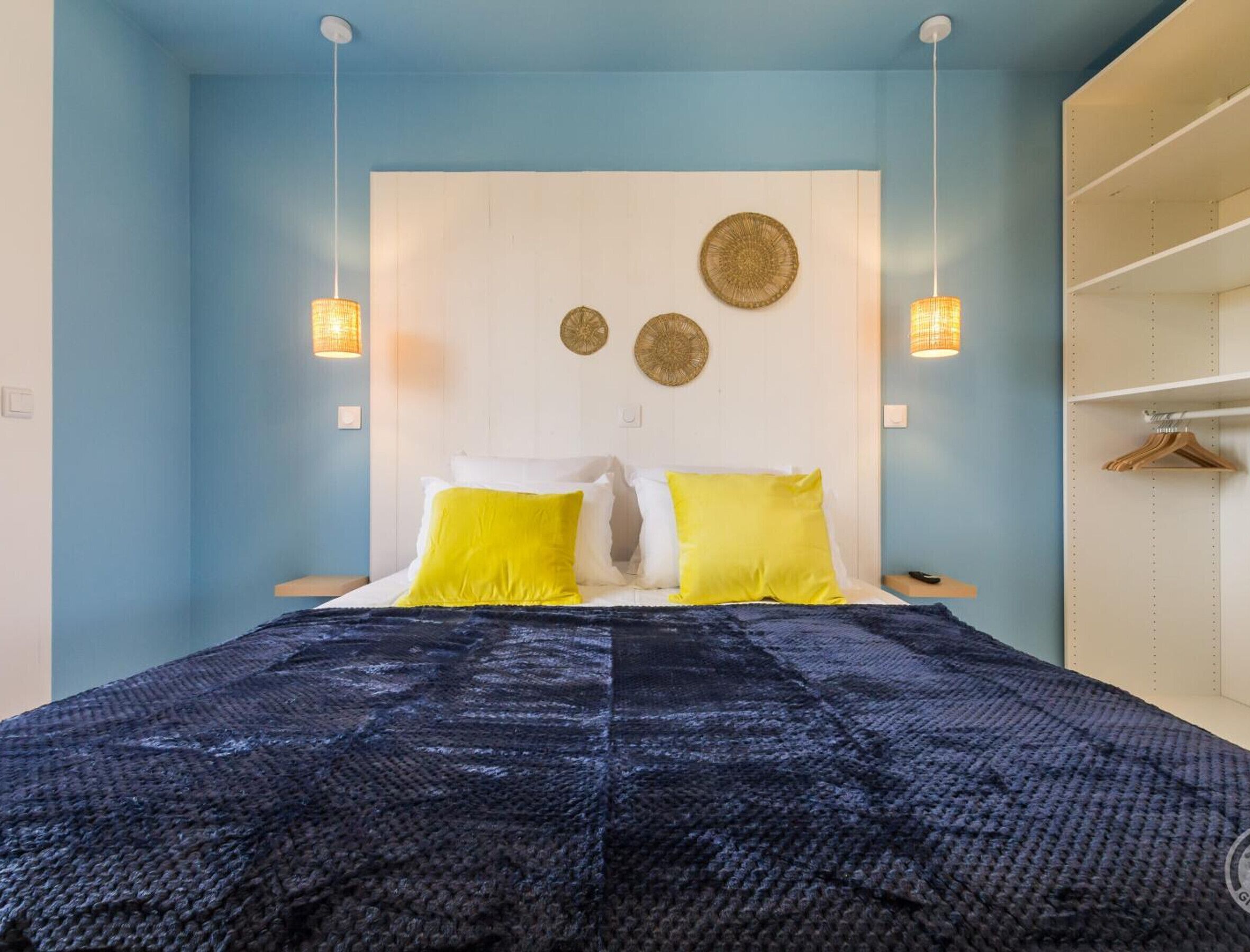 A bedroom with a bed, two bedside lamps, a wardrobe, and wall decorations.