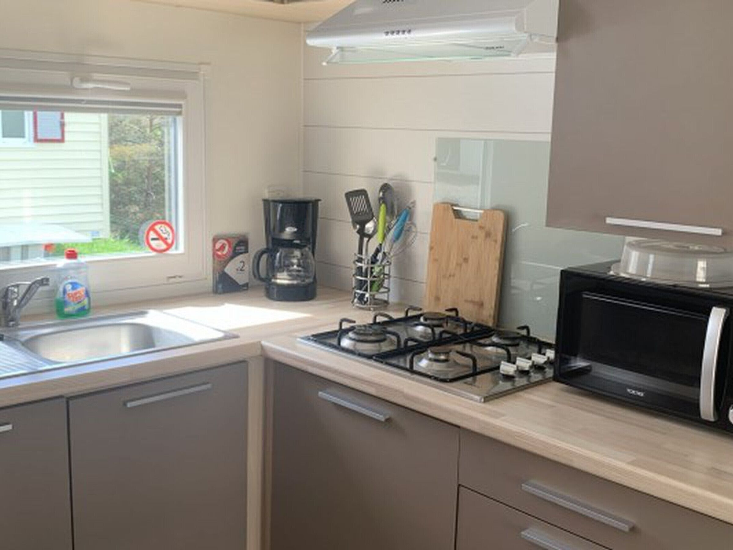 A kitchen with a gas stove, a coffee maker, and a microwave.
