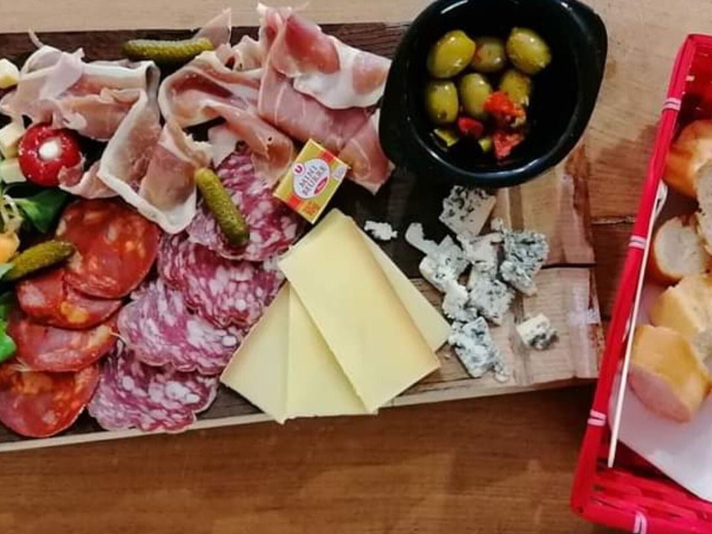 A charcuterie board with various meats, cheeses, olives, and pickles.