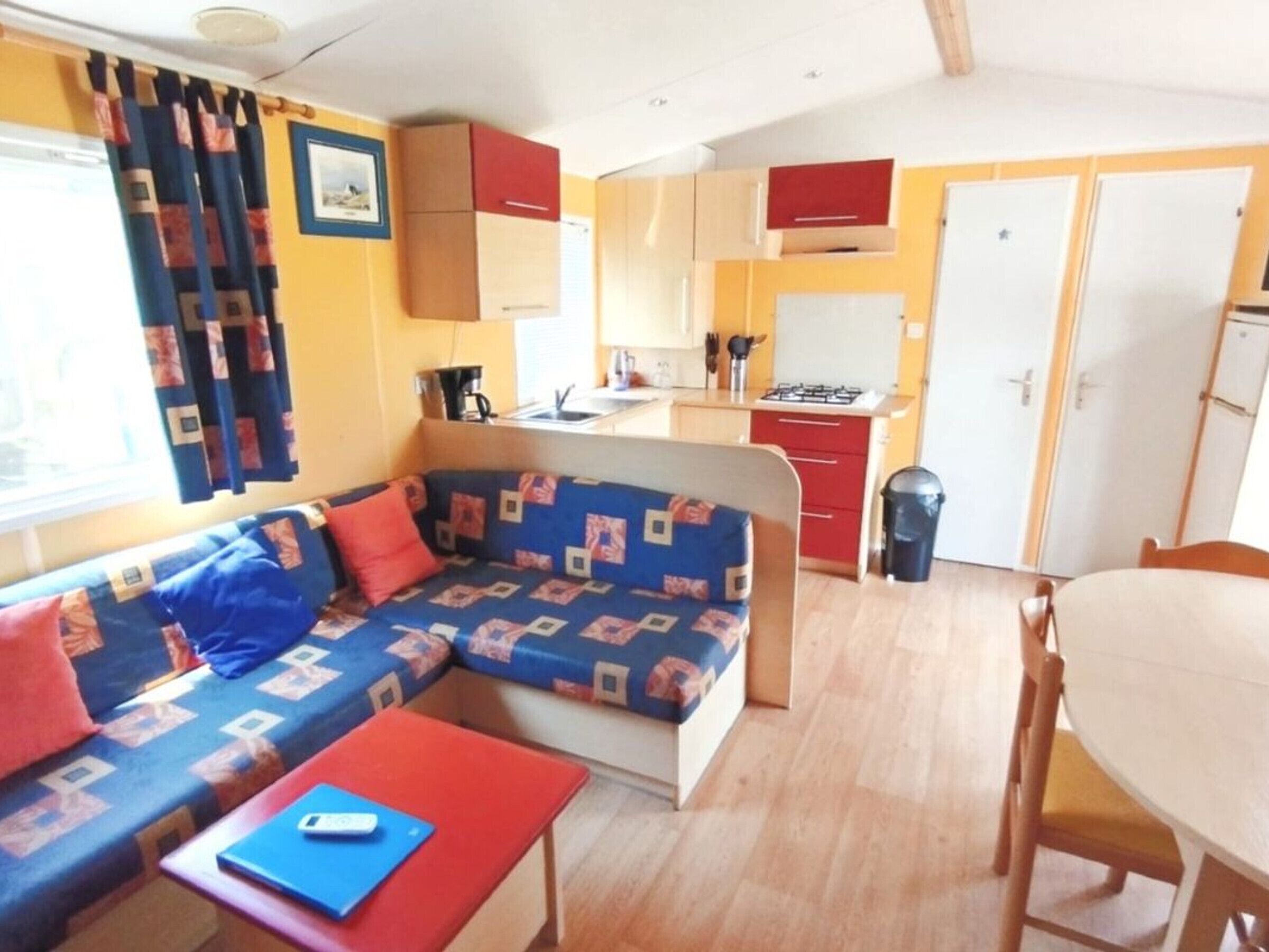 A compact living space with a sofa, a small table, a dining table, and a kitchenette.