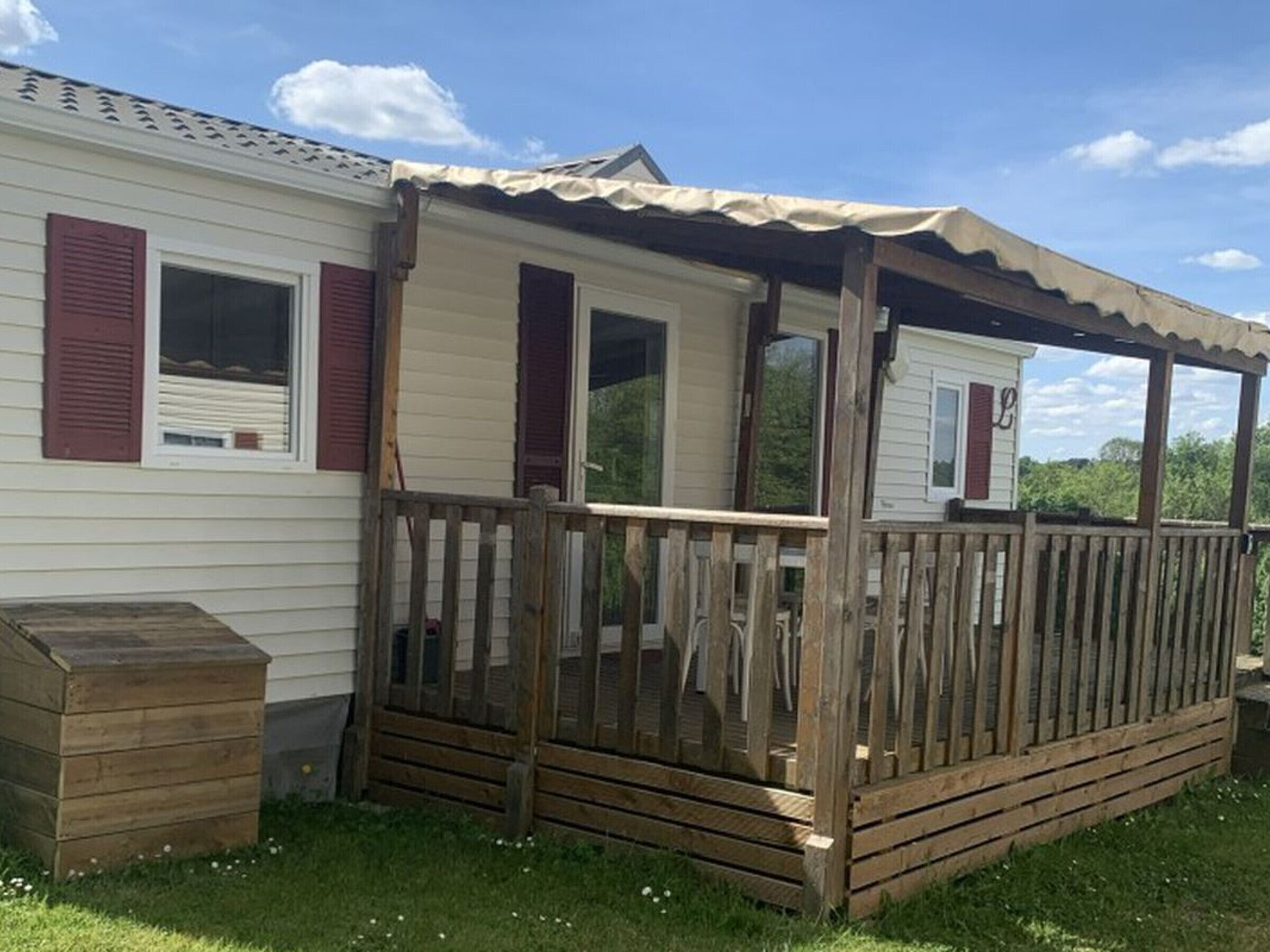 En campingvogn med træterrasse og overdækket veranda.