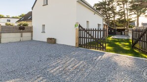 A white building with a triangular roof, a gravel driveway, and a wooden fence. - Comfortable house, pets allowed - 8 guests (Saint-Germain-sur-Ay)