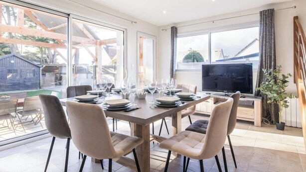 A dining area with a table set for four, a television, and a large window with a view of the outside. - Comfortable house, pets allowed - 8 guests (Saint-Germain-sur-Ay)