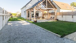 A house with a covered patio, a gravel driveway, and a well-maintained lawn. - Comfortable house, pets allowed - 8 guests (Saint-Germain-sur-Ay)